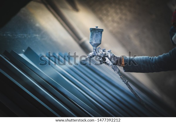 Man painting\
metal products with a spray\
gun