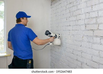 Man Painting Old Brick Wall In White Color With Paint Sprayer