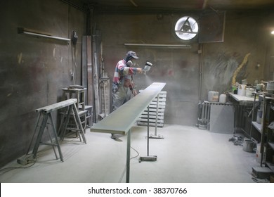 Man Painting With Spray Paint Gun In His Home Workshop