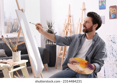 Man painting in studio. Using easel to hold canvas
