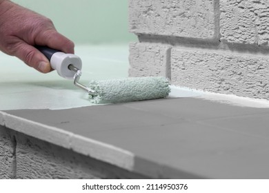 Man Painting Tiles On A Fireplace With A Paint Roller. Do It Yourself Concept