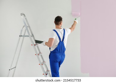 Man Painting Wall With Light Pink Dye Indoors, Back View