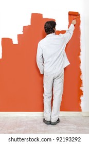 Man, painting a wall with orange paint and a paint roller