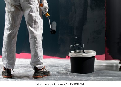 Man Painting A Wall. Painter In Red Overall Painting Wall In Black Color