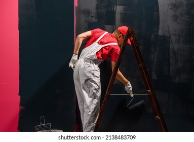 Man Painting A Wall. Painter In Red Overall Painting Wall In Black Color