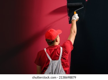 Man Painting A Wall. Painter In Red Overall Painting Wall In Black Color