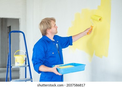 man painting wall in yellow color with roller. Renovation, repair and redecoration concept