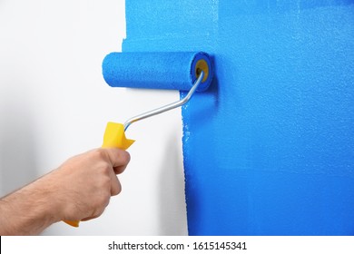 Man painting white wall with blue dye, closeup. Interior renovation