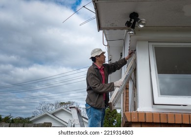 Man Painting Window Frames Of An Old House. Home Maintenance Project.