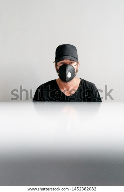 man paints with paint\
and a brush wooden door with white paint in a black cap and a\
t-shirt Respirator