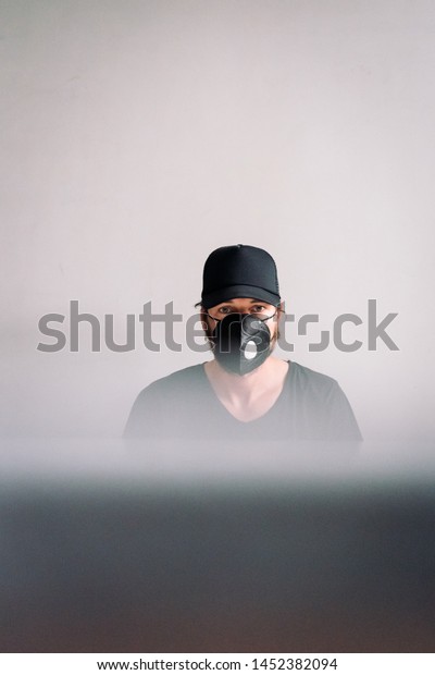 man paints with paint
and a brush wooden door with white paint in a black cap and a
t-shirt Respirator