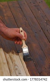 man paints wood in dark color - Shutterstock ID 1778314742