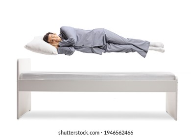 Man In Pajamas Sleeping And Floating Above A Bed Isolated On White Background