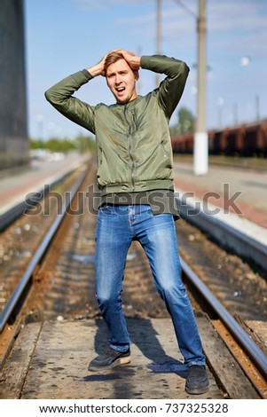 A man in a panic stands on the rails