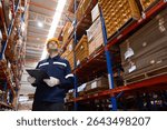 Man paper warehouse worker using clipboard checking inspecting quality cardboard in storage. Large industry in paper product line manufacturing. Employee level wear uniform and helmet yellow.