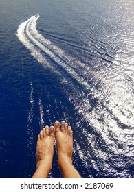 Man Parasailing Over Ocean With Feet And Boat In View