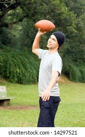 A Man, In A Park, Standing, Throwing A Football. - Vertically Framed