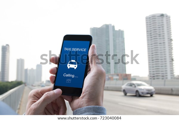Man passenger calling taxi via internet application\
on mobile smart phone with blurred background of car driving on the\
road in the city