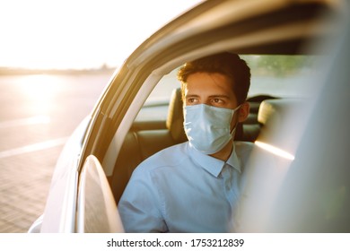 Man Passenger In Protective Sterile Medical Mask In The Taxi Car During An Epidemic In Quarantine City. Health Protection, Safety And Pandemic Concept. Covid - 19.