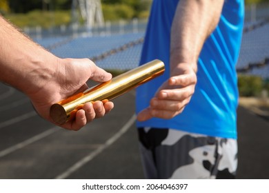 Man Passing Baton To His Partner At Stadium, Closeup