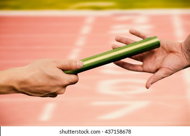 Man passing the baton to partner on track against close up of the track starting point