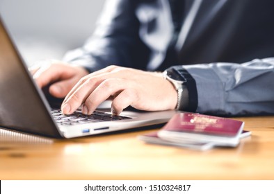 Man With Passport And Laptop. Travel Document And Identification. Immigrant Writing Electronic Application For Citizenship. Apply For Digital Visa. Online Flight Ticket Or Web Check In.