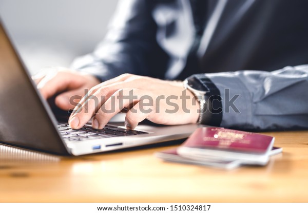 Man
with passport and laptop. Travel document and identification.
Immigrant writing electronic application for citizenship. Apply for
digital visa. Online flight ticket or web check
in.
