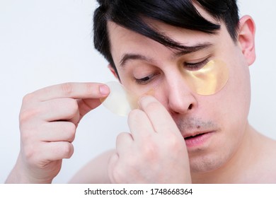 Man With Patches Under His Eyes. Men's Facial Spa. The Guy Puts Balm On His Lips.