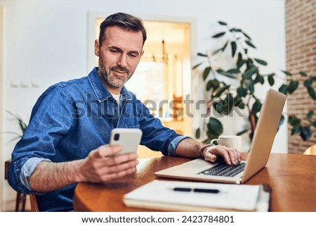 Man paying with 2FA two factor authentication using his phone and laptop at home