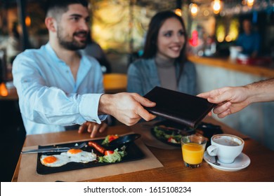 Man Paying Bill With Cash In Restaurant