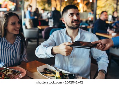 Man Paying Bill In Restaurant