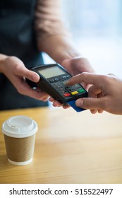 Man Paying Bill Through Payment Terminal In Cafe