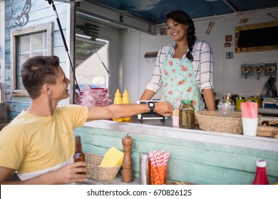 Man paying bill through smartwatch at food truck counter - Powered by Shutterstock