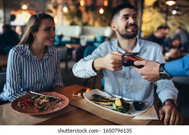 man paying contactless with visa or master card in restaurant
