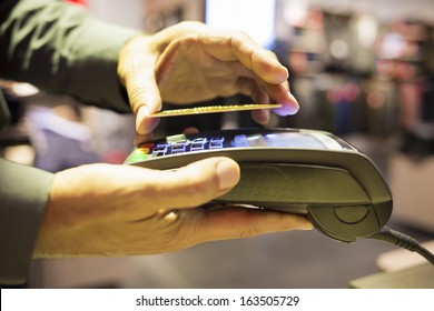 Man Paying With NFC Technology On Credit Card, In Clothing Store