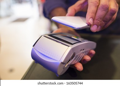 Man Paying With NFC Technology On Mobile Phone, In Pharmacy