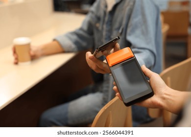 Man paying with smartphone via terminal in cafe, closeup - Powered by Shutterstock