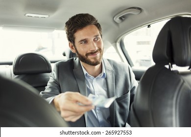 Man paying the taxi with the cash - Shutterstock ID 265927553