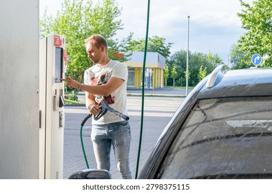 Man Paying at Touchscreen Terminal While Refueling Car at Gas Station