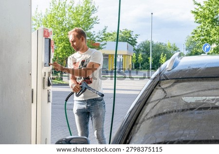 Man Paying at Touchscreen Terminal While Refueling Car at Gas Station