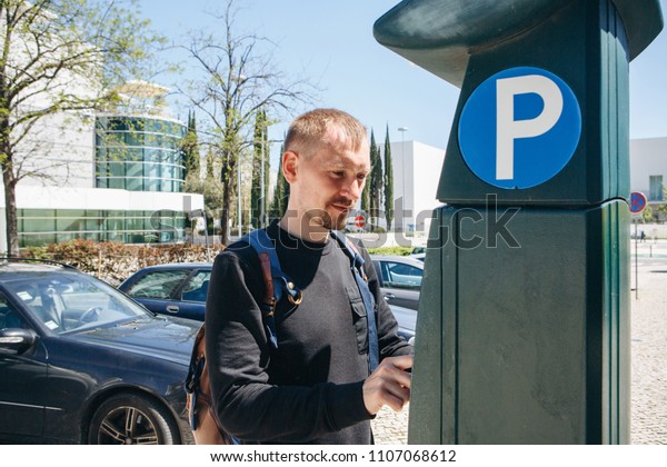 A man pays for Parking using a special machine\
to pay in Lisbon in Portugal