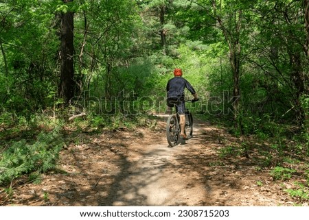 Man pedals mountain bike through overgrown forest trails