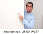 A man peeking behind wall showing wow face while pointing at the wall