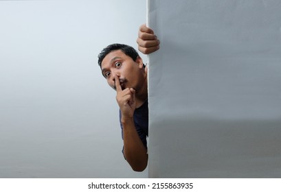 Man Peeking Behind The Wall With Silent Hand Gesture