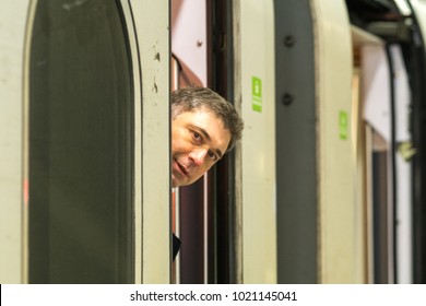 Man Peeking Out From Behind The Train Door