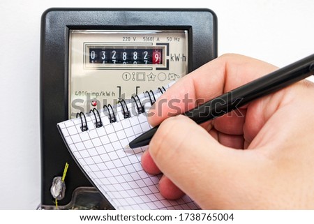 Man with pen and notepad writes the electrical meter readings. Payment of utility services.