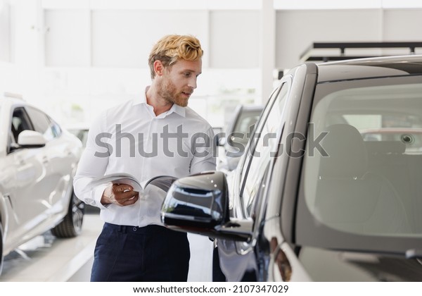 Man pensive customer male buyer client in white\
shirt read car papers documents agreement choose auto want buy new\
automobile in showroom vehicle dealership store motor show indoor\
Sales concept.
