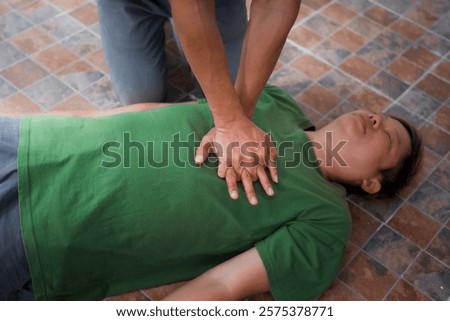 A man performing CPR on another man lying down, placing his hands on the patient’s chest to ensure safety, monitor heart rate, provide emergency services, and maintain health care and body integrity