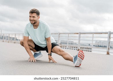 A Man Performing a Dynamic Stretching Exercise Outdoors on a Cloudy Day Near a Waterfront - Powered by Shutterstock