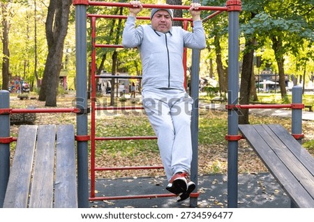 Man performing pull ups on horizontal bar during outdoor training in park. Concept of physical activity, persistence and fitness goals